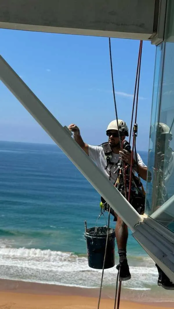 Rope access technician working on the glazing of a beachfront apartment building