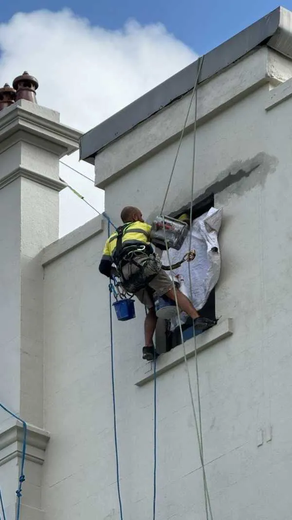 Rope access repair at a window opening in a rendered parapet wall